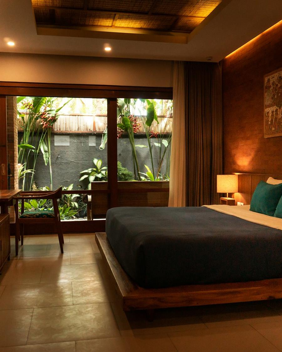 A warm hotel room opening onto a planted courtyard.